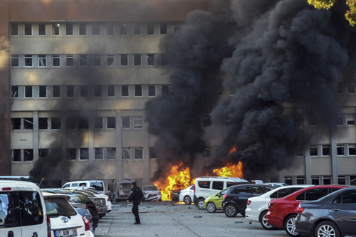 A police officer walks past by a fire after an explosion that killed people and wounded several others in southern city of Adana, Turkey, on Thursday (AP photo)